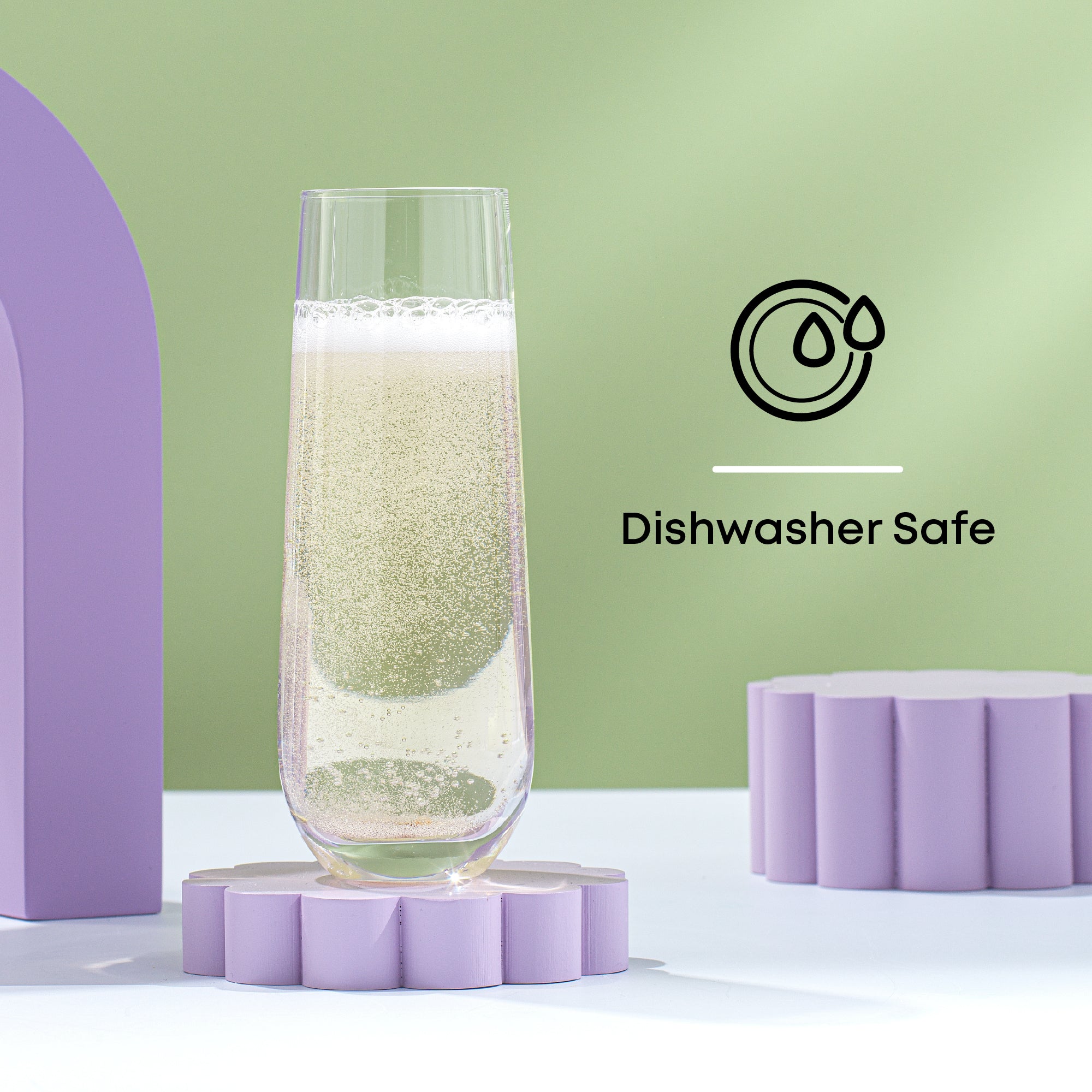 A tall, clear glass filled with sparkling water sits on a purple flower-shaped platform against a green background. Text on the right reads "Dishwasher Safe" with a dishwasher-safe symbol.