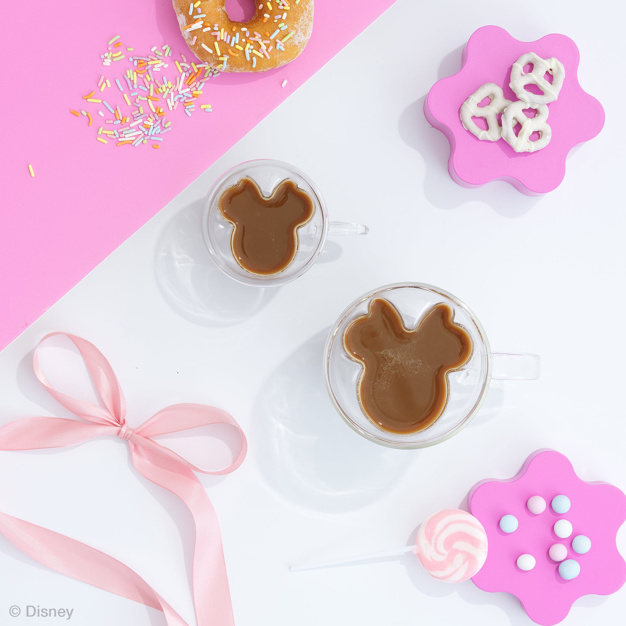 Bunny-shaped cookies on a pink and white background with sprinkles and a bow.