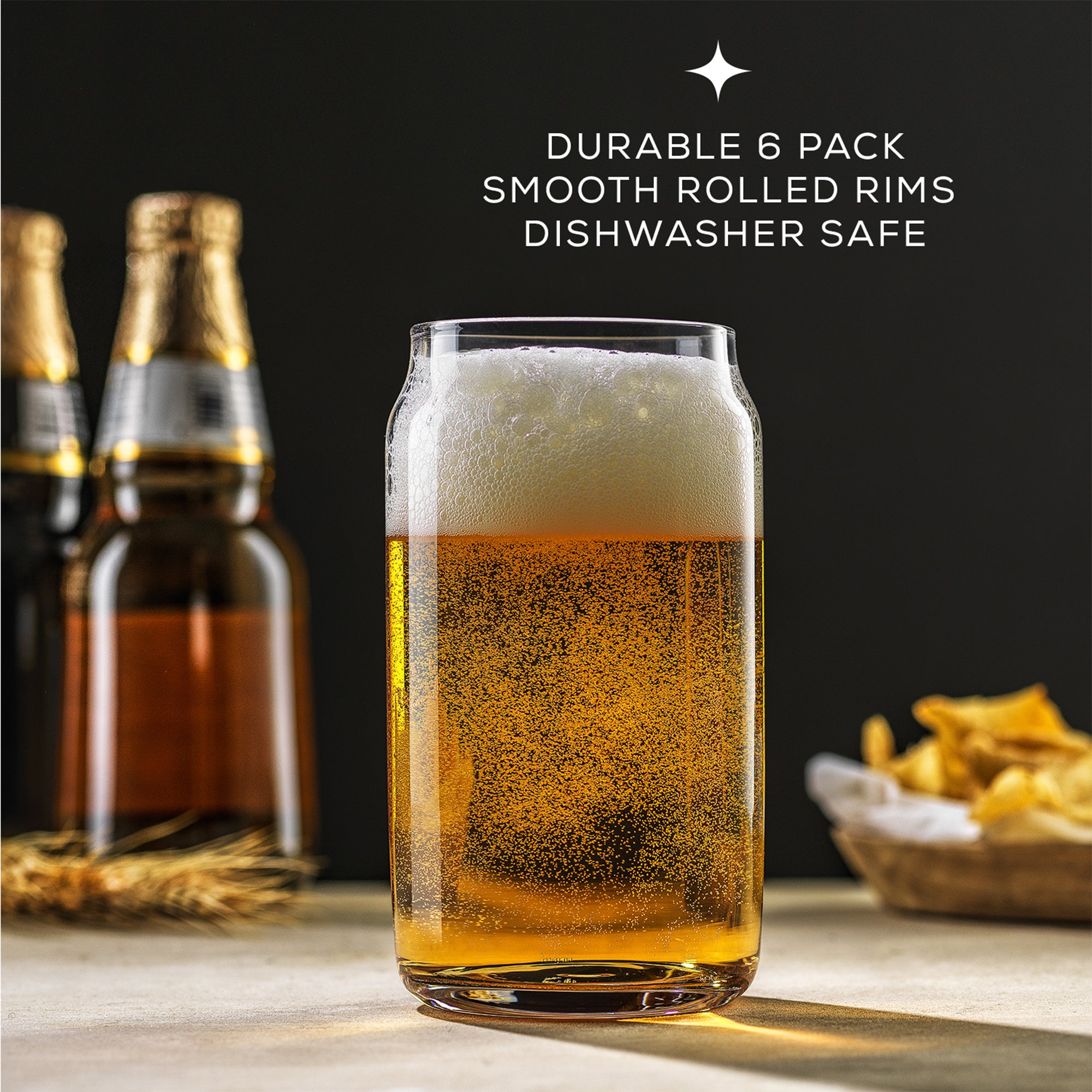 A clear, half-full beer glass showcasing effervescent bubbles with 'JoyJolt Classic Can Tumblers', 'smooth rolled rims', and 'dishwasher safe' labels, positioned on a table