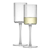 Two clear, tall and slender white wine glasses with a fluted design and a single stem. One glass is empty and the other is filled with a white wine.