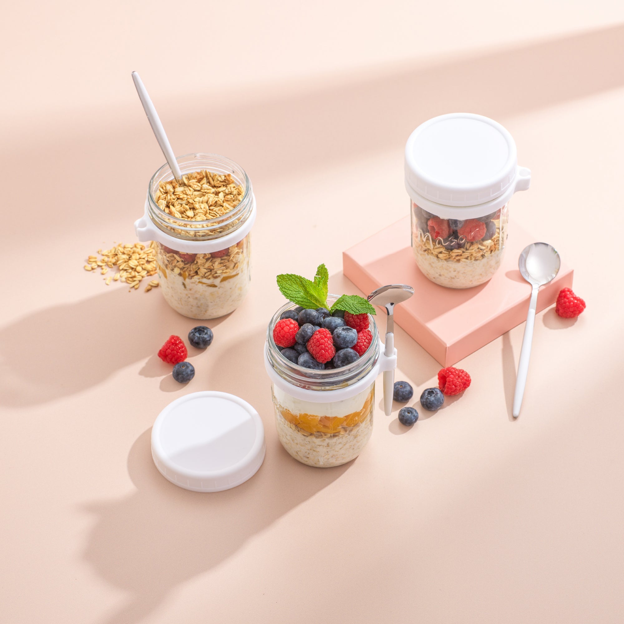 Three overnight oats container high angle photo filled with fruits, yogurt, and granola.