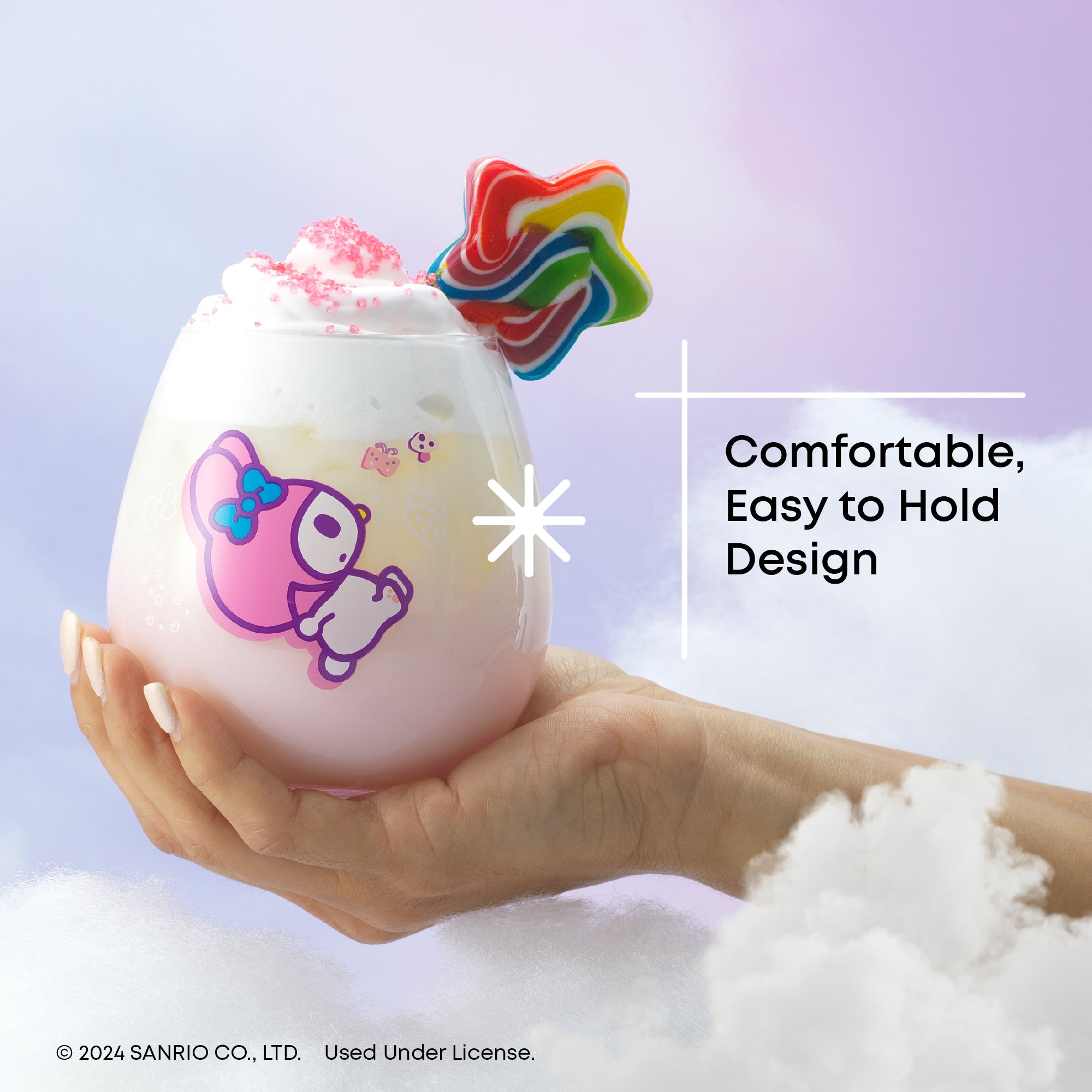 A hand holding a pink ombre Hello Kitty and Friends glass featuring My Melody. The glass has a pink drink topped with whipped cream and a star rainbow lollipop.