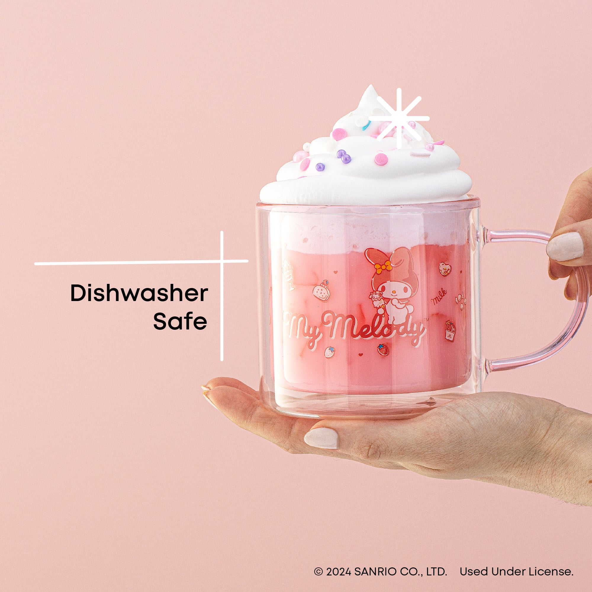 A person holding a pink My Melody mug with whipped cream on top. The mug has a white image of My Melody. Text on the image reads "Dishwasher Safe".