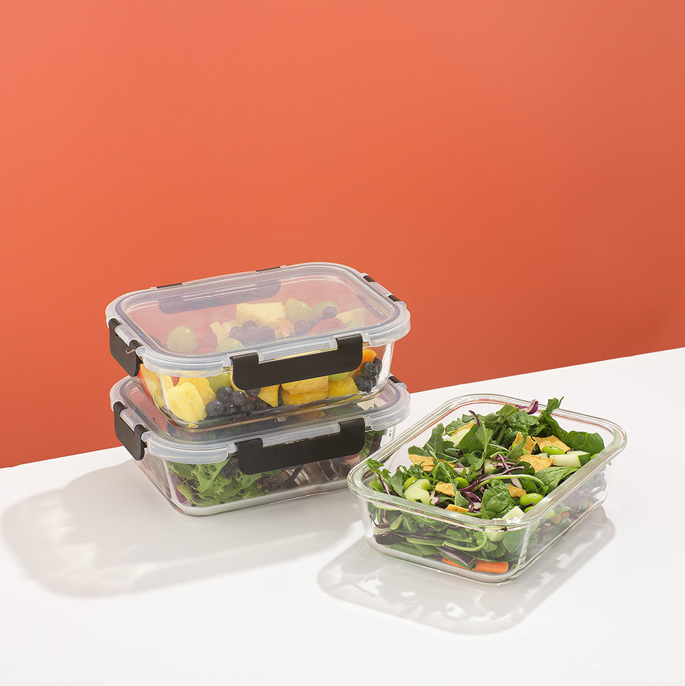 Clear food storage containers with salad on a white surface against a red background