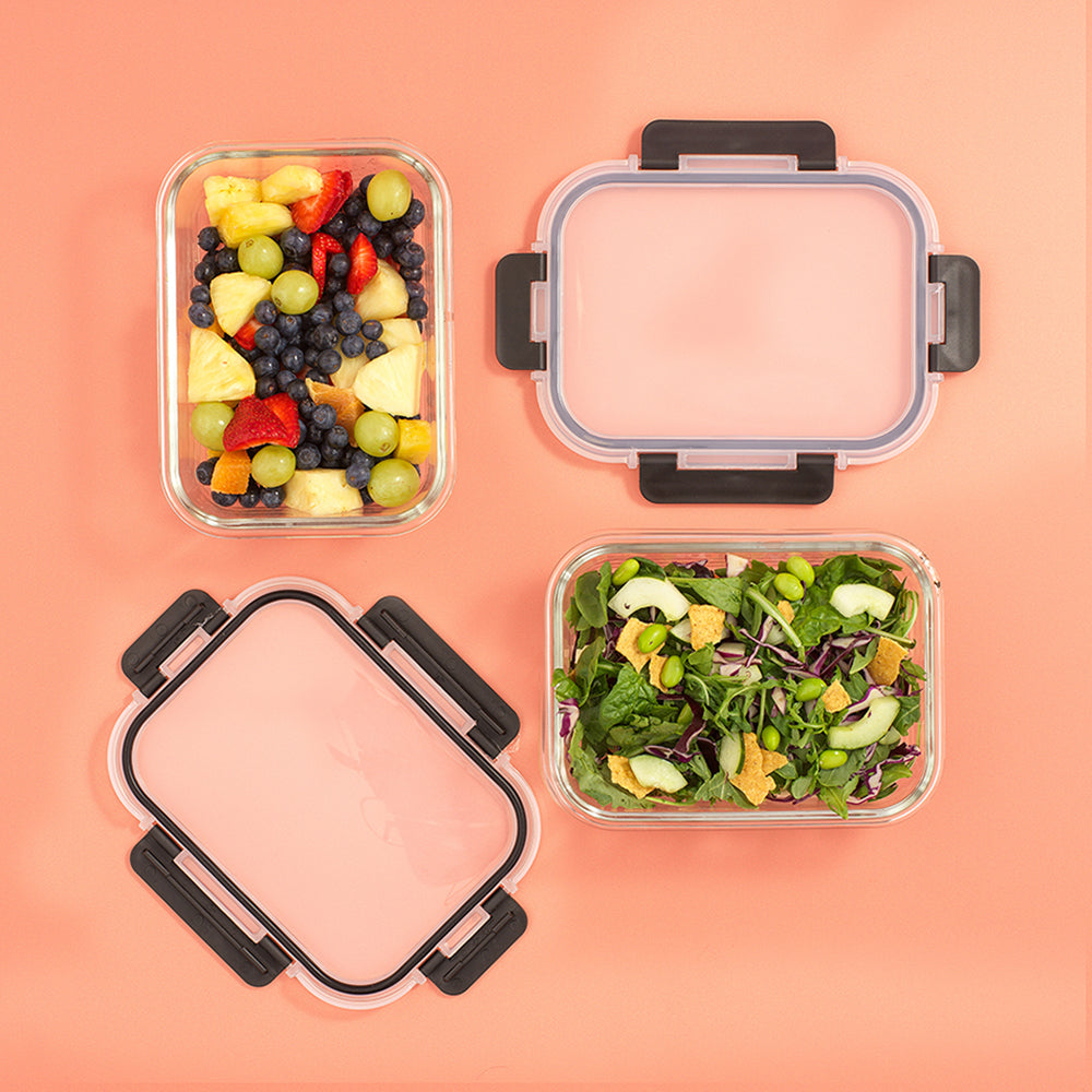 Two containers with fruit salad and green salad on a peach background