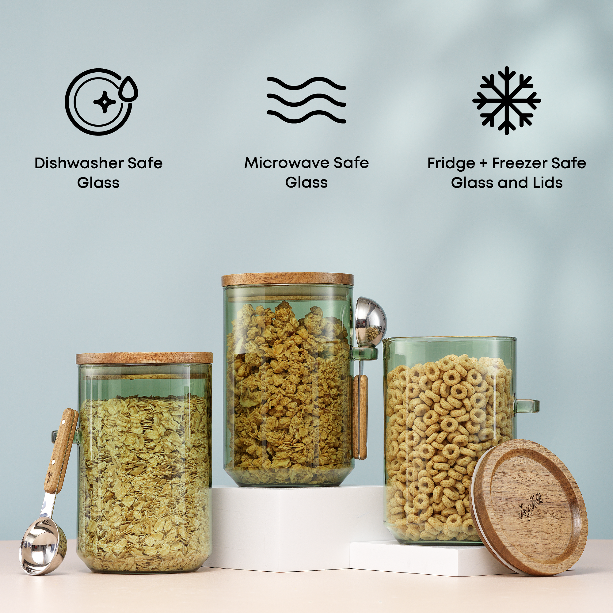 Glass storage jars with wooden lids and measuring spoons on a light blue background with care icons: microwave and dishwasher safe glass, fridge and freezer safe glass and lids.
