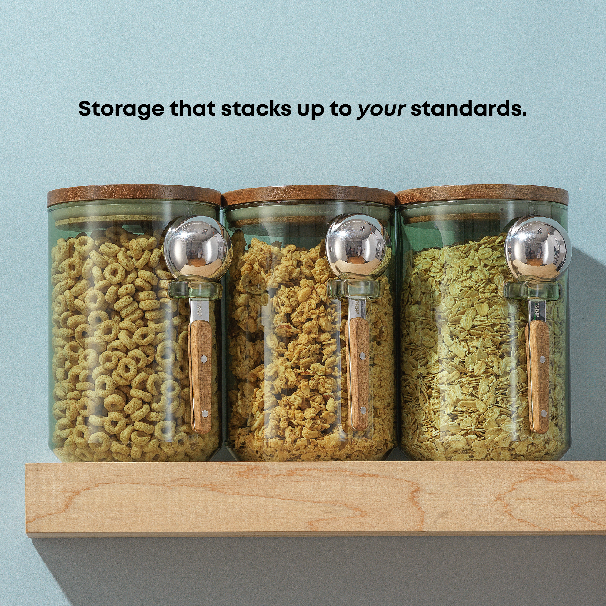 Three glass jars with wooden lids and different cereal inside, on a light blue background.