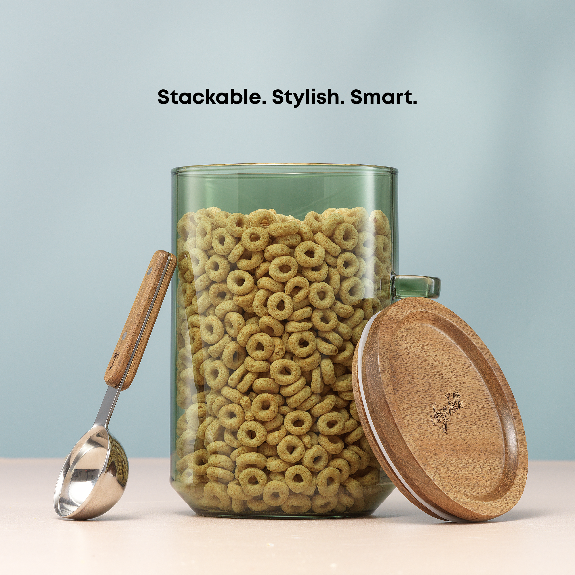 Glass jar with wooden lid and handle filled with cereal, accompanied by a metal scoop on a light blue background.