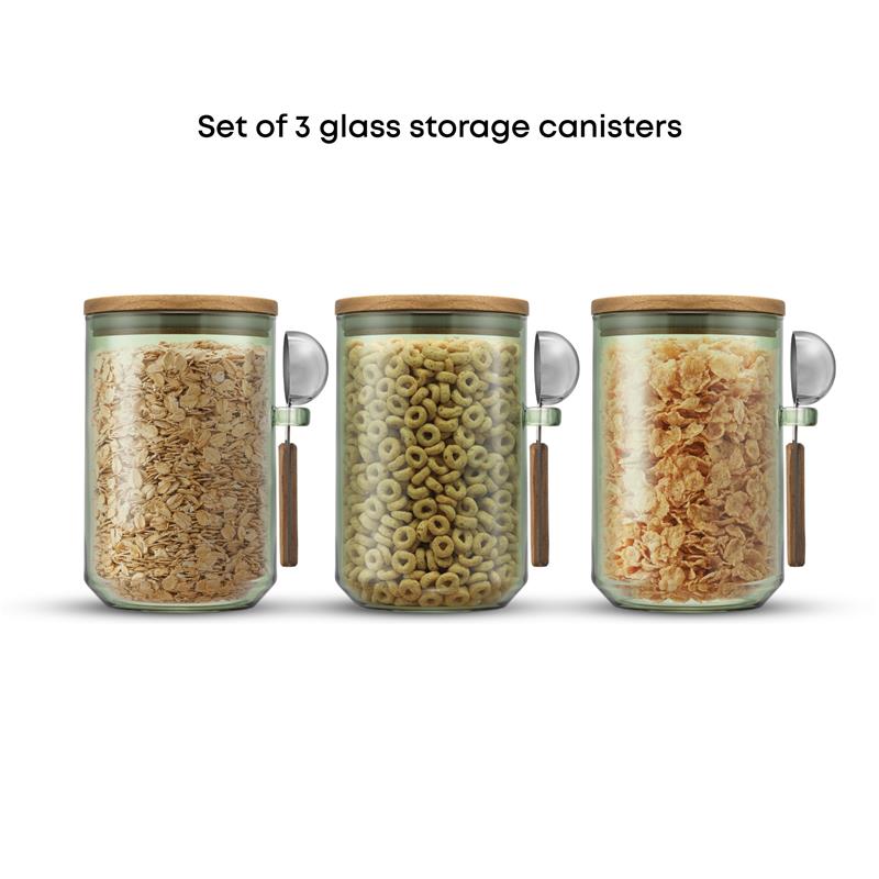 Set of three glass storage canisters with wooden lids, each containing different types of cereal.
