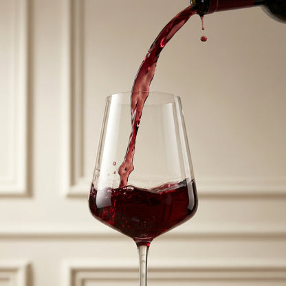Red wine being poured into a glass with a neutral background