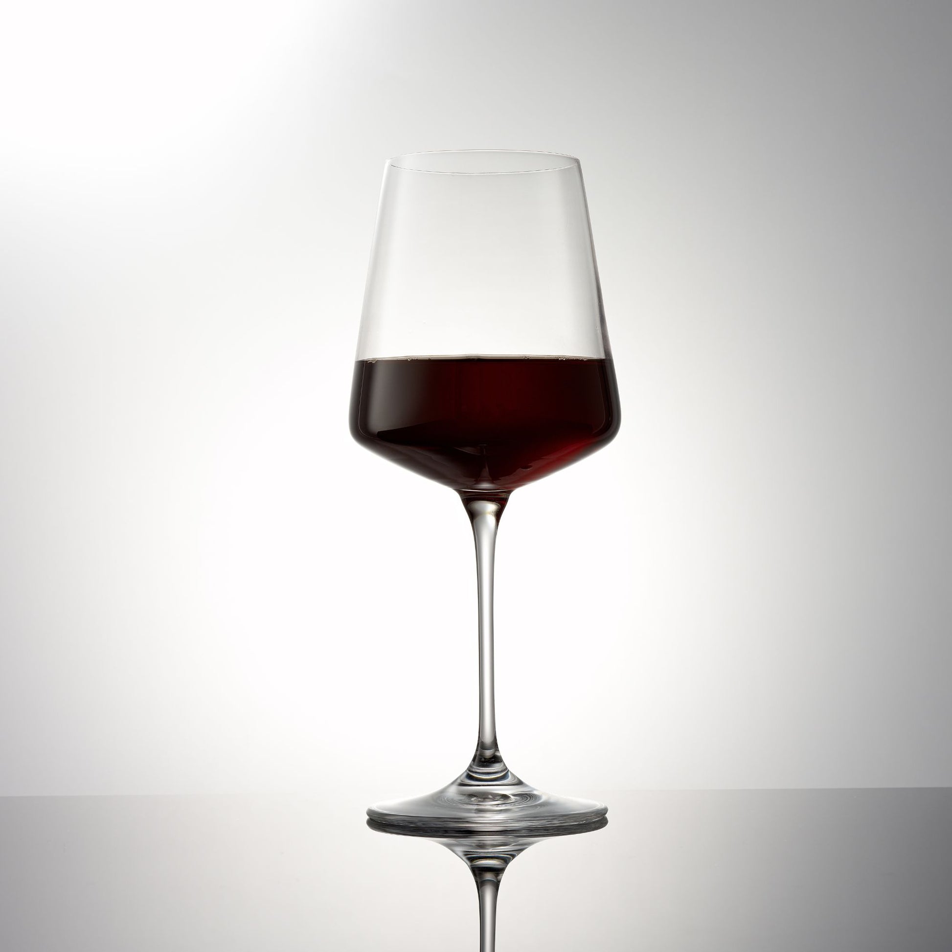 Wine glass with red wine on a gray background