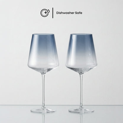 Two dishwasher-safe glass wine glasses on a light gray background