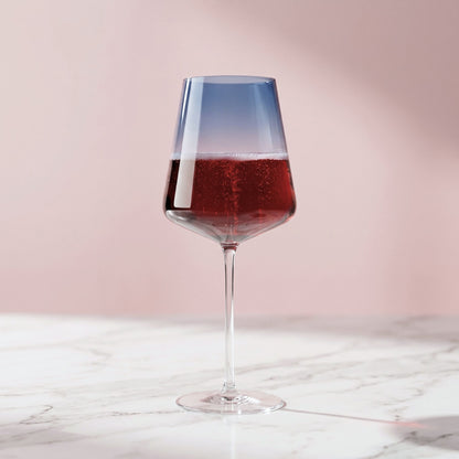 Wine glass with red wine on a marble surface and pink background