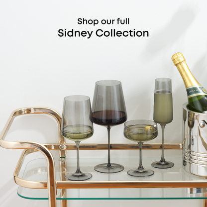Stemmed glasses and a bottle on a bar cart with 'Shop our full Sidney Collection' text.