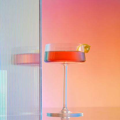 Cocktail in a glass with a lemon twist against a colorful background