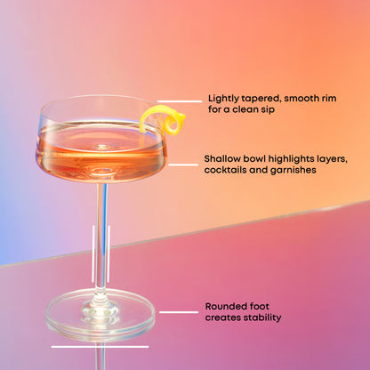 Cocktail glass with a lemon twist on a gradient background, featuring text about the glass design: smooth rims, shallow bowl for garnishes, rounded foot for stability.