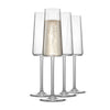 Set of four clear champagne flutes with one containing a bubbly beverage on a white background