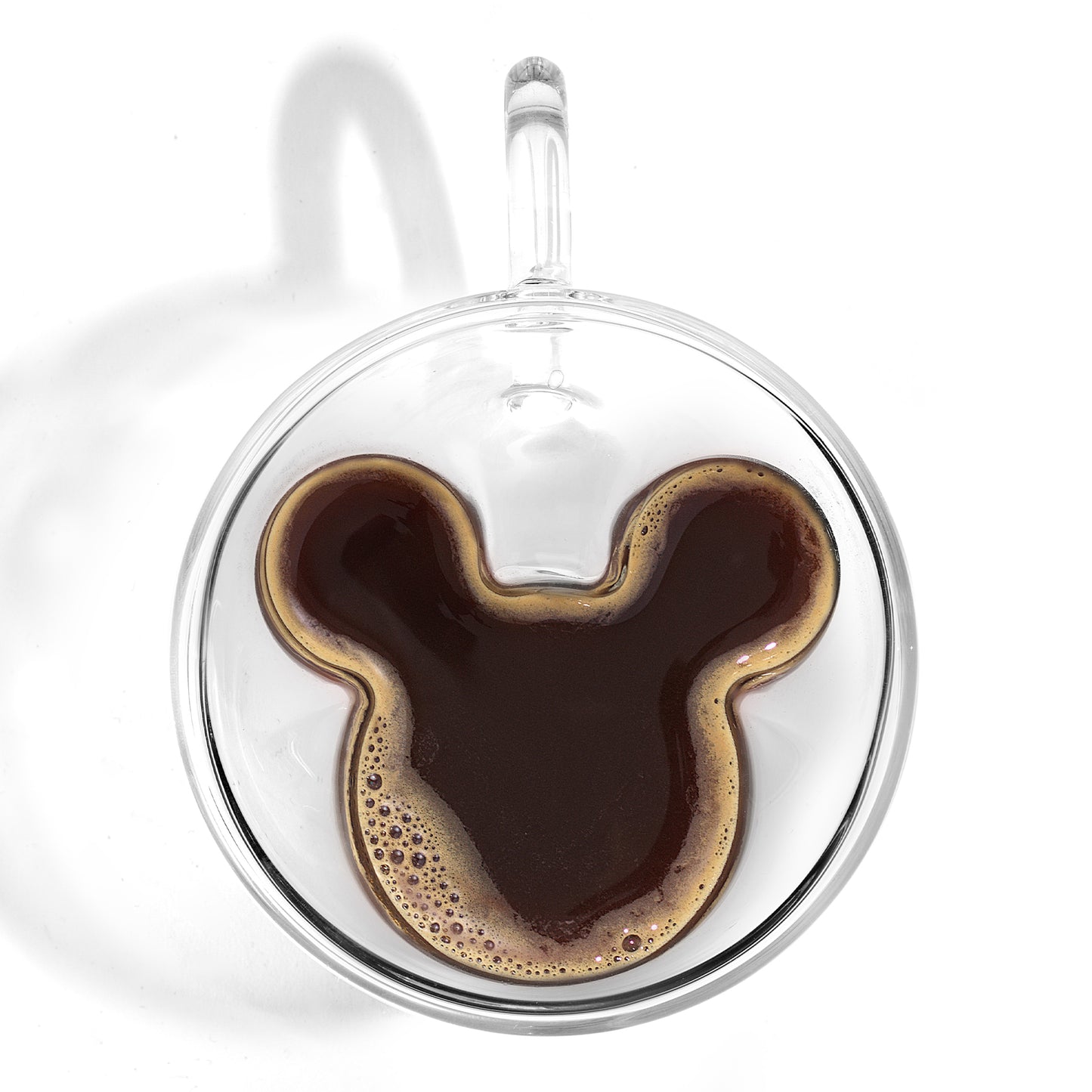 a espresso glass with handle filled with espresso, filling Mickeys ears, on a white background