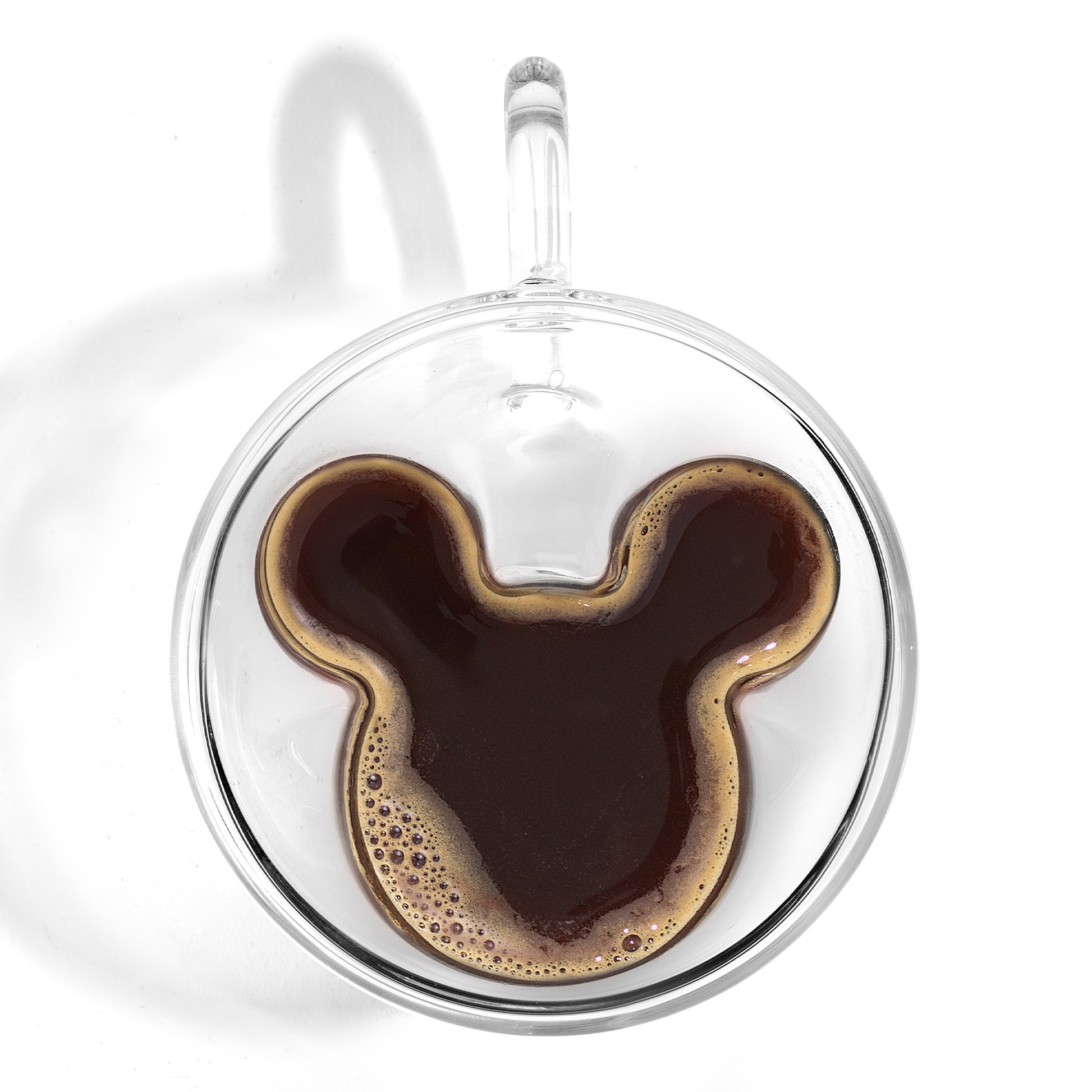 a espresso glass with handle filled with espresso, filling Mickeys ears, on a white background