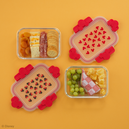 Two glass containers with food inside and red Mickey and Minnie ear lids on an orange background