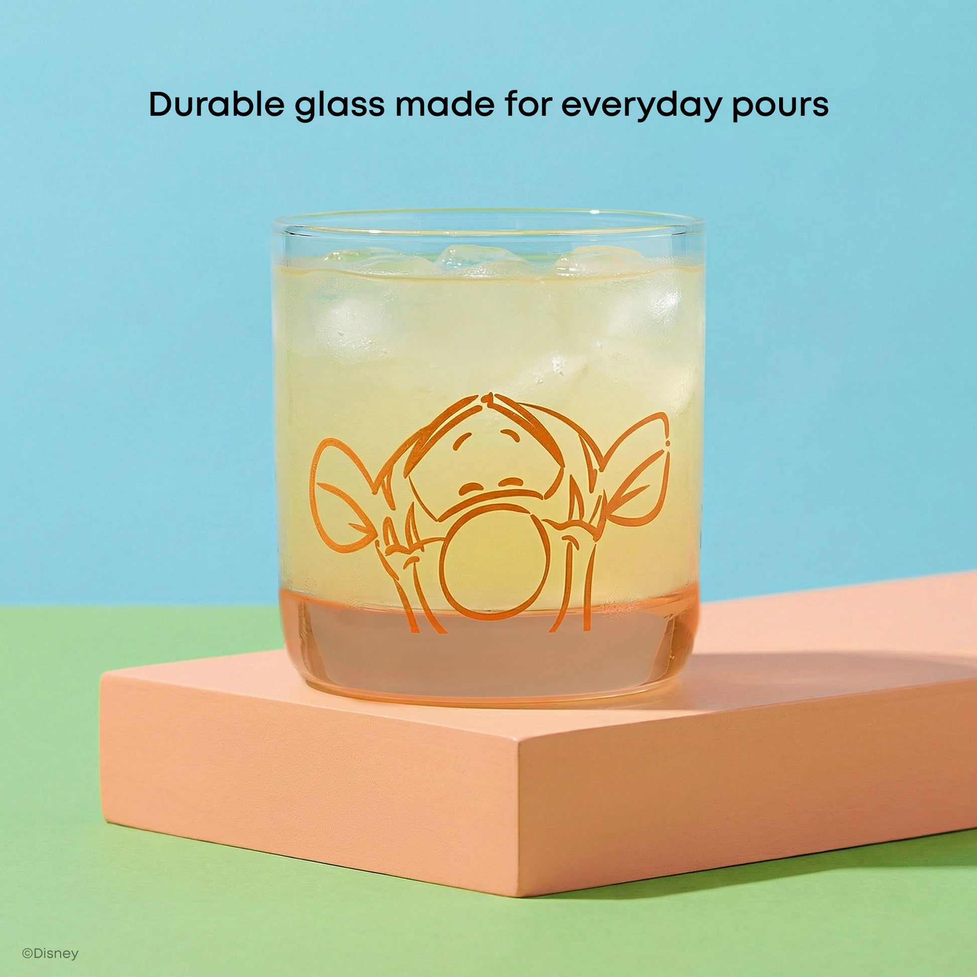 Glass with a cartoon character design of Tigger in orange on a colorful background with text "durable glass made for everyday pours" 