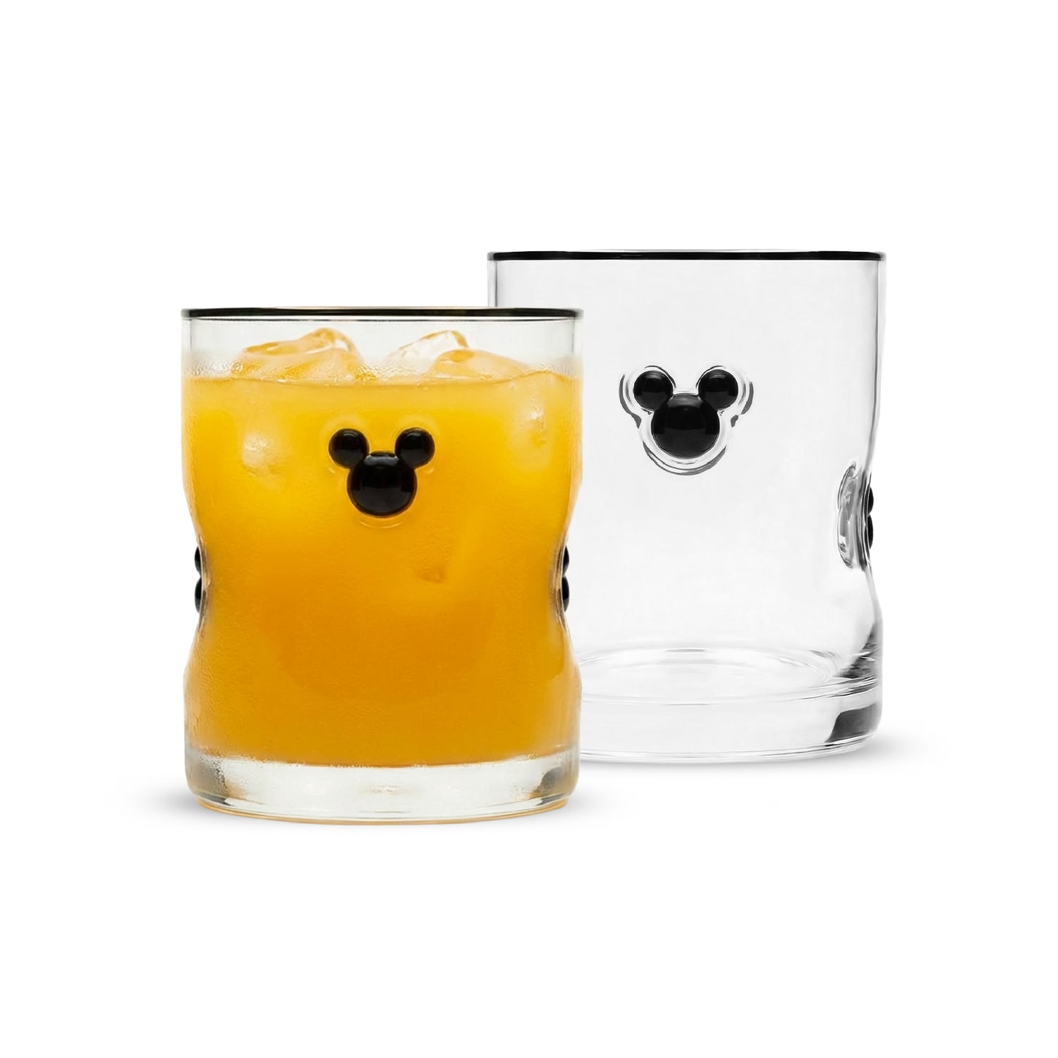 Two clear lowball glasses with black Mickey Mouse head details, one filled with an orange drink and ice, and one empty, shown on a white background.