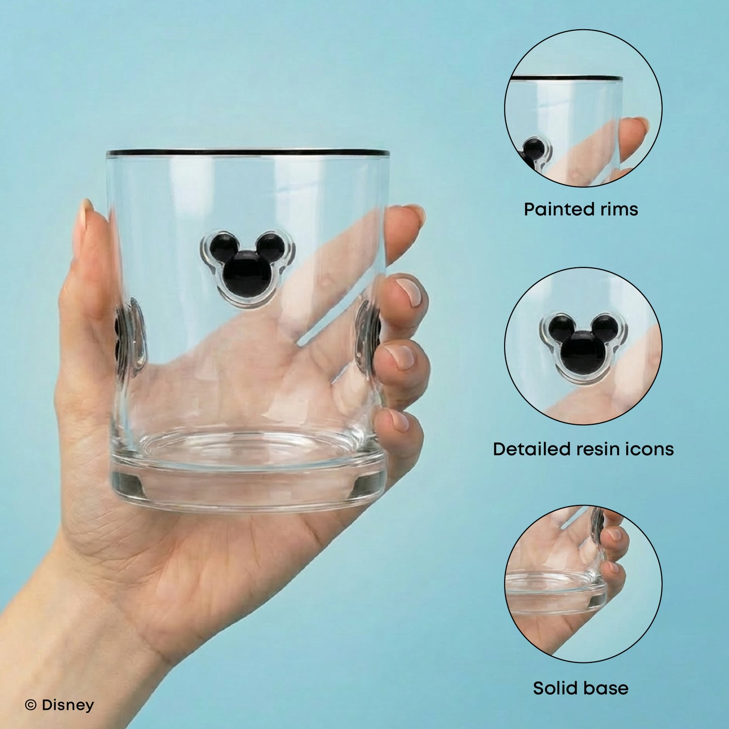 A hand holds a clear glass tumbler with a black rim and a black Mickey Mouse head icon on the front. Three circular inset callouts on the right highlight features: painted rims, detailed resin icons, and a solid base.