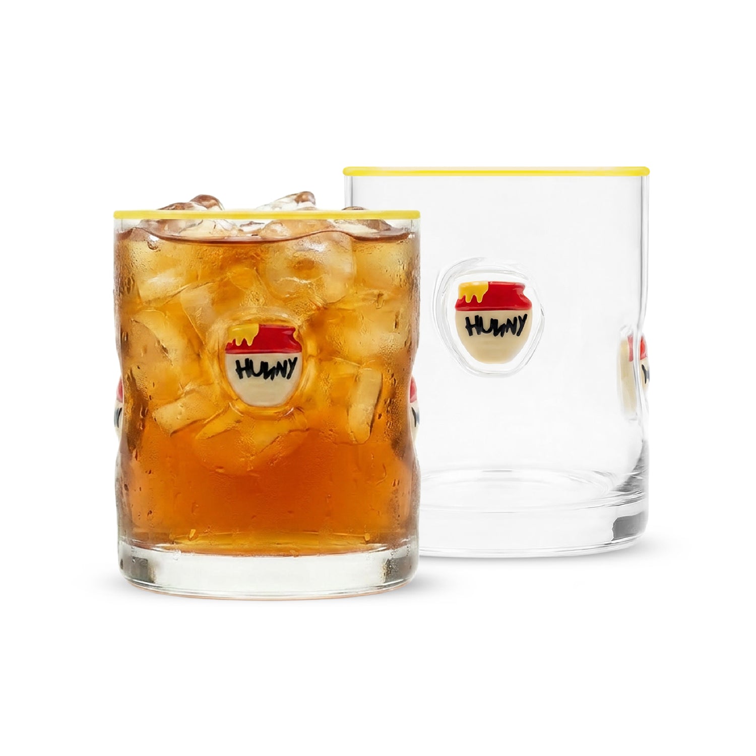 Two clear glass tumblers with a yellow rim and a circular 'HUNNY' resin icon, shown on a white background. One tumbler is filled with an iced amber drink, and the other is empty.