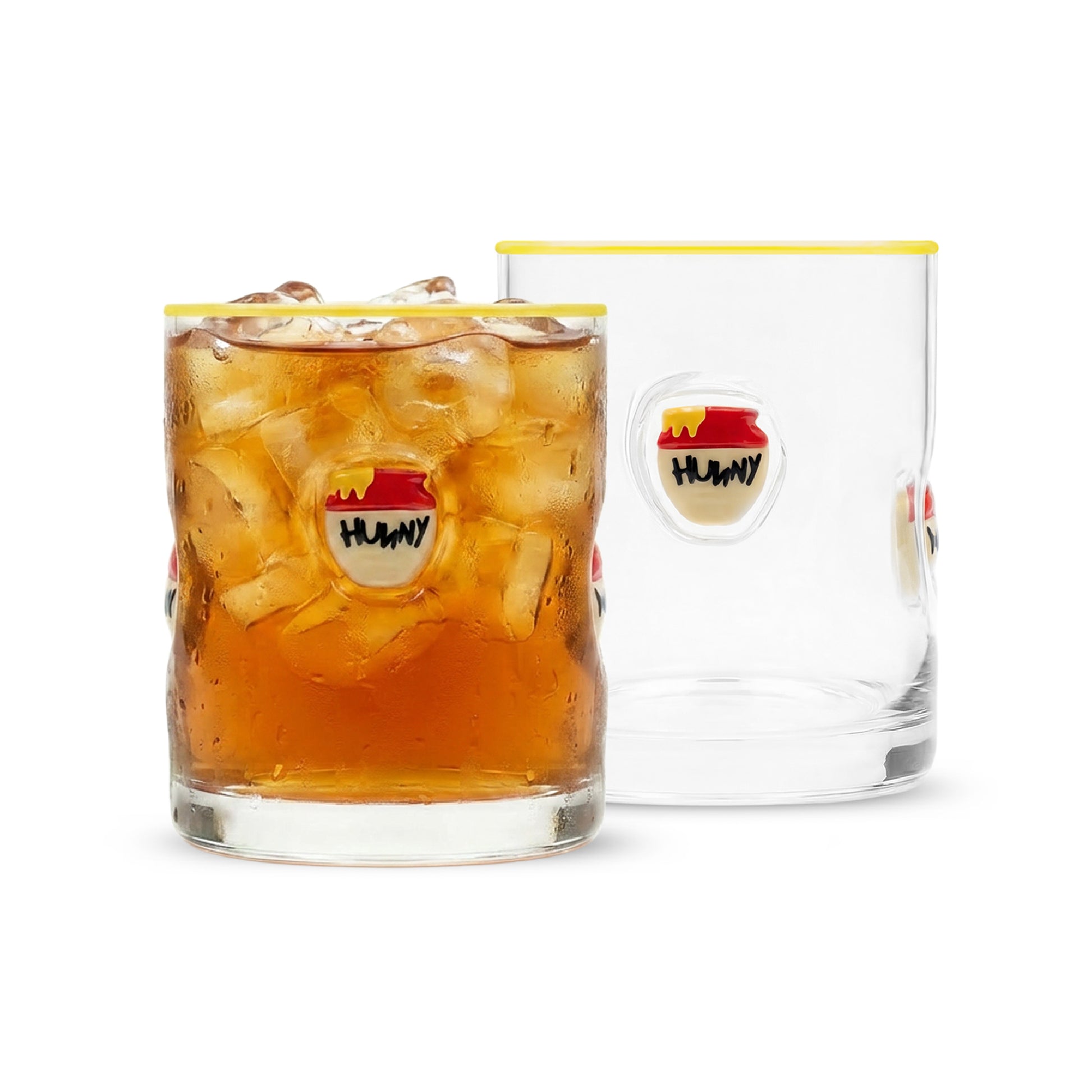 Two clear glass tumblers with a yellow rim and a circular 'HUNNY' resin icon, shown on a white background. One tumbler is filled with an iced amber drink, and the other is empty.