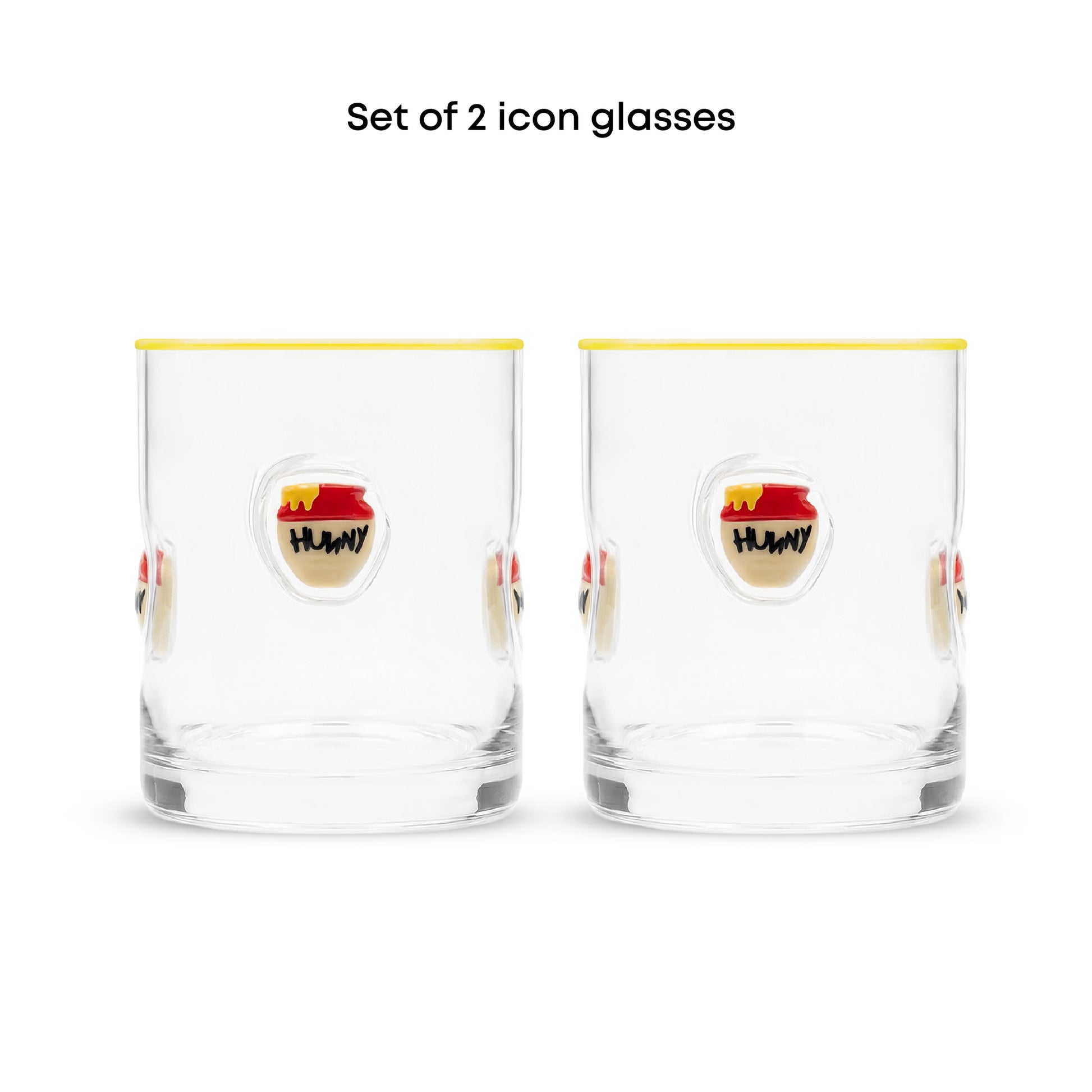 Set of 2 clear glass tumblers with a yellow rim, featuring a cartoon honey pot illustration on the front with the text 'HUNNY' and the caption 'Set of 2 icon glasses' above.
