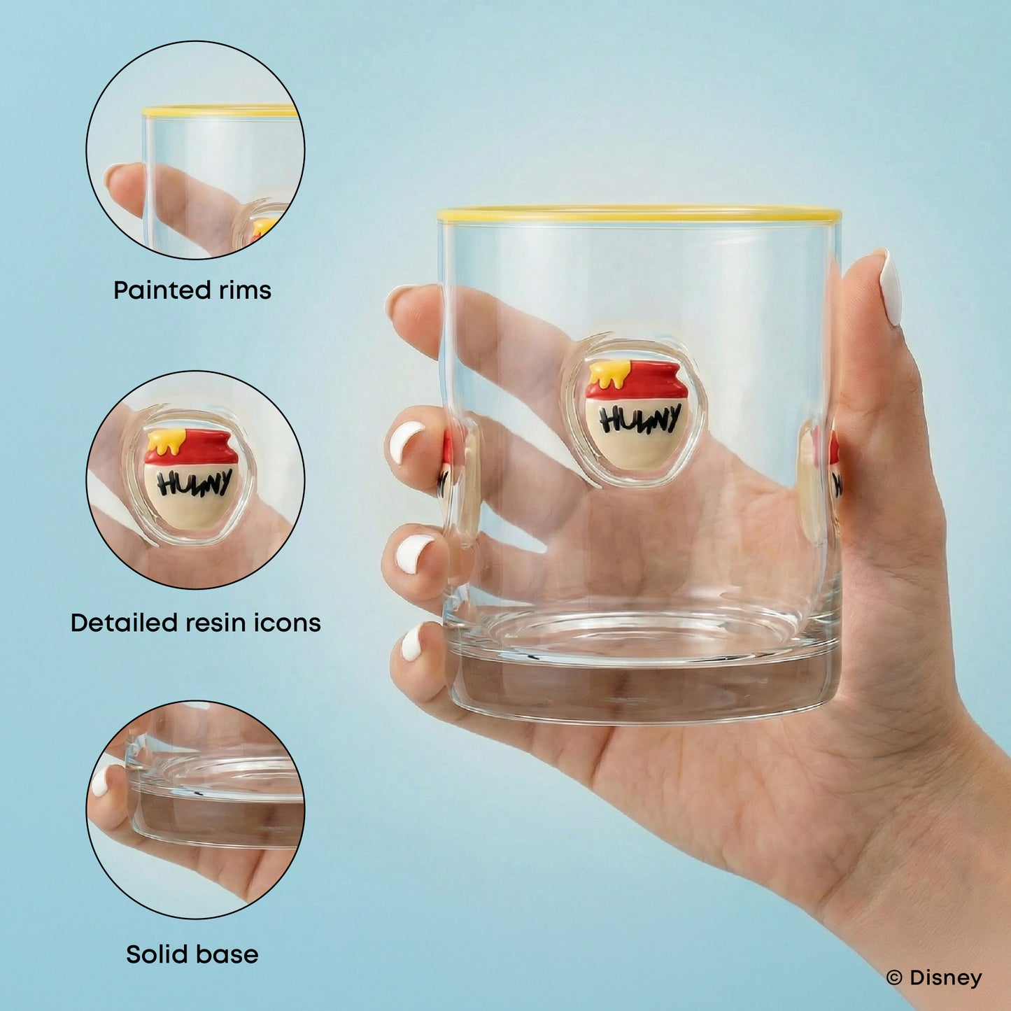 A hand holds a clear drinking glass with a yellow rim and a small multicolor HUNNY logo on the front. Three circular inset callouts on the left highlight product features: painted rims, detailed resin icons, and a solid base.