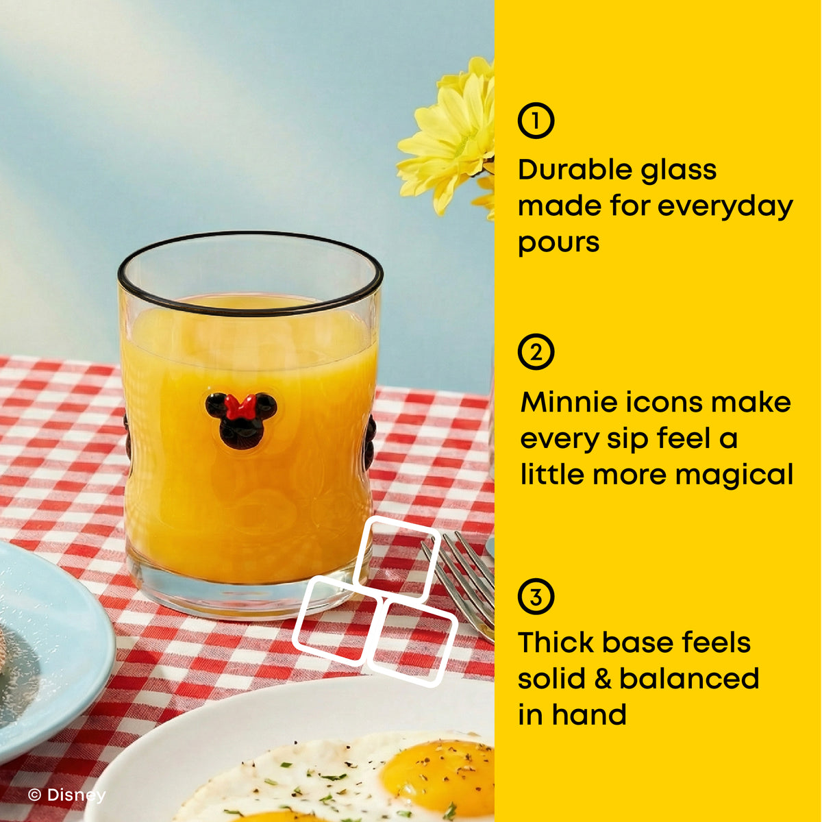 A Mickey Mouse-themed glass of orange juice on a red-and-white checkered tablecloth, with a bright yellow text panel on the right listing product features. The glass has a black rim and a black Mickey silhouette with a small red bow tie detail.