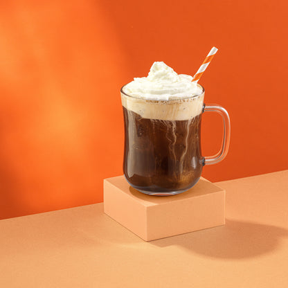 A full glass mug with whipped cream on top, on an orange background