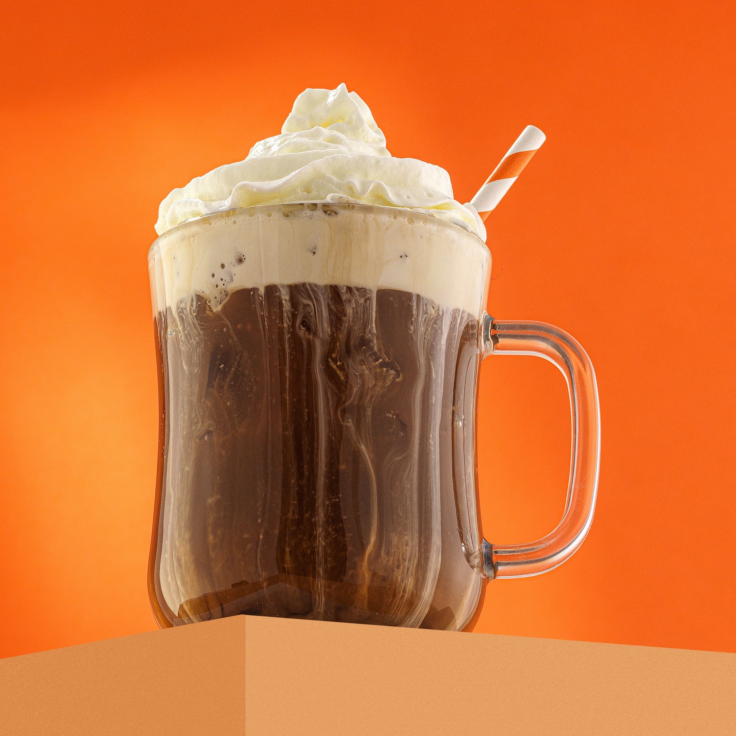 A full glass mug with whipped cream on top, on an orange background