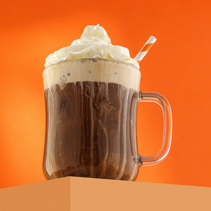 A full glass mug with whipped cream on top, on an orange background