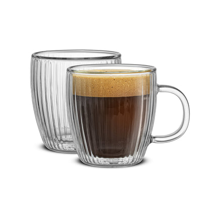 Two clear glass mugs with a fluted glass design, with one containing a shot of espresso on a white background
