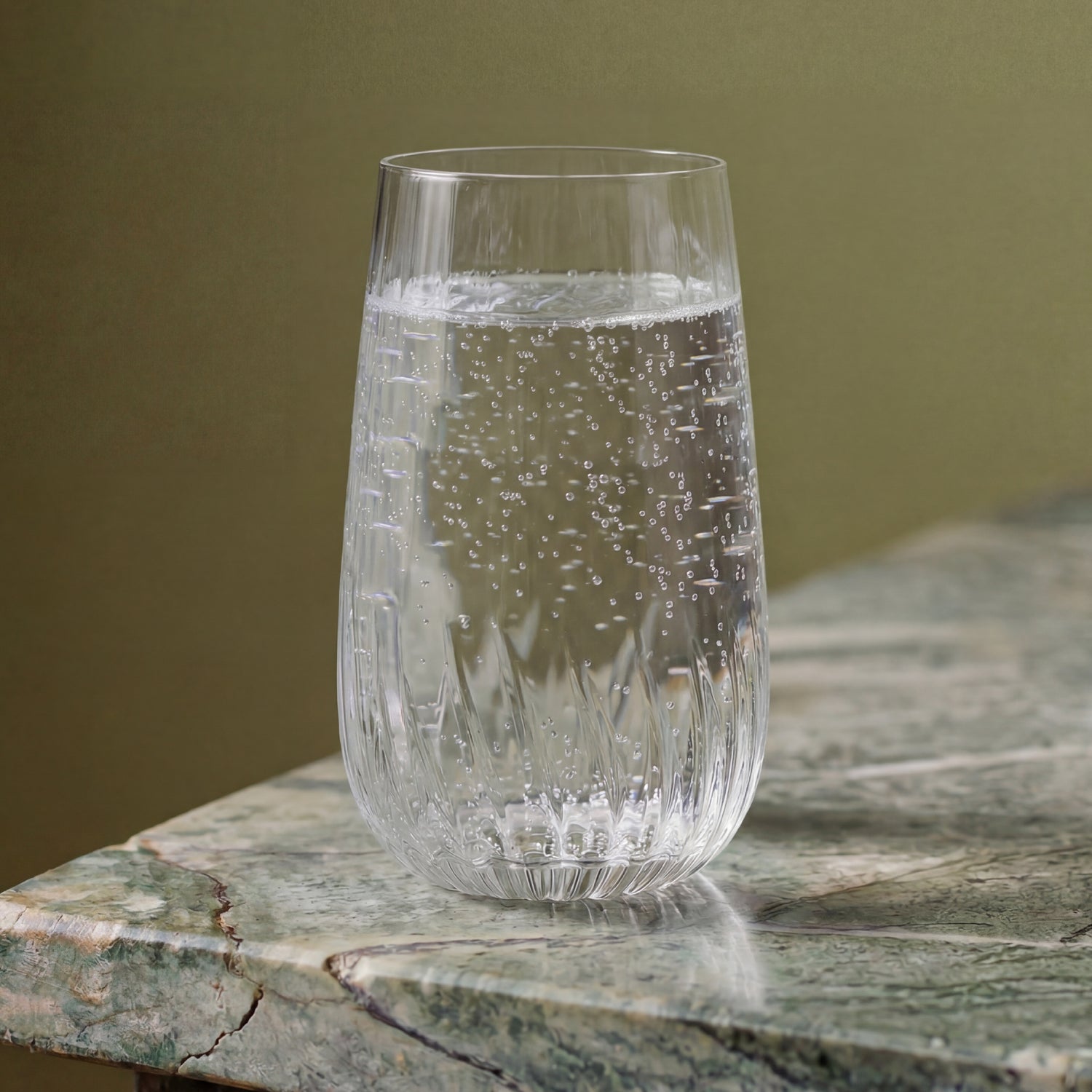 Clear glass with water on a stone surface against a green background