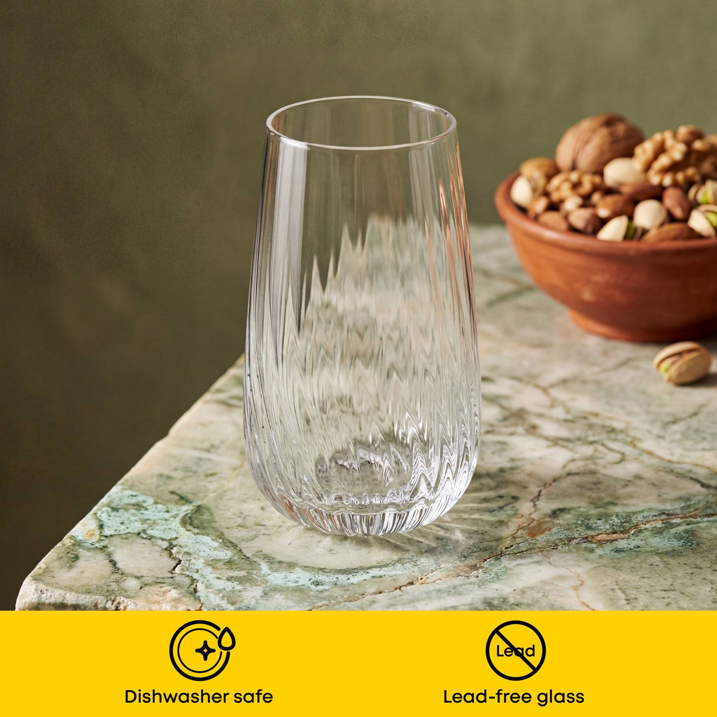 Clear glass on a marble surface with a bowl of nuts, featuring 'Dishwasher safe' and 'Lead-free glass' labels.