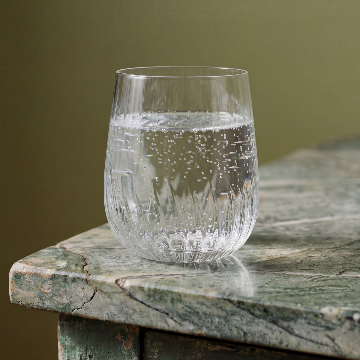 Clear glass with water on a textured surface