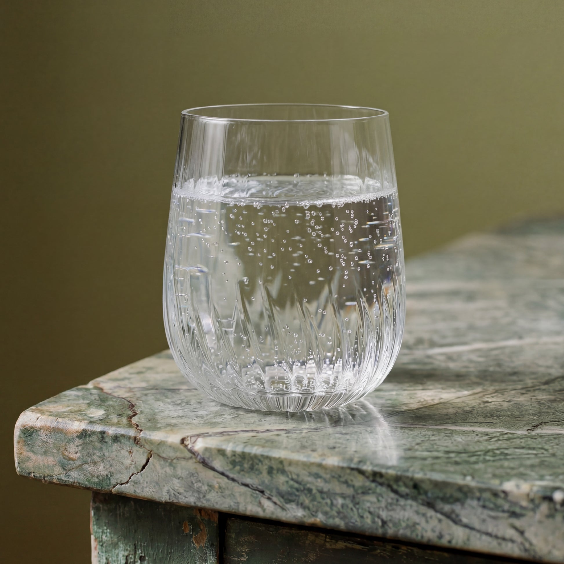 Clear glass with water on a textured surface