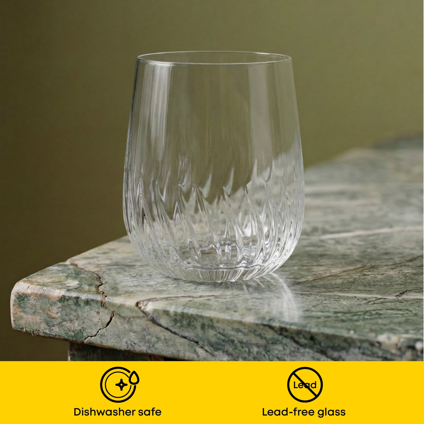 Clear glass tumbler on a stone surface with a green background