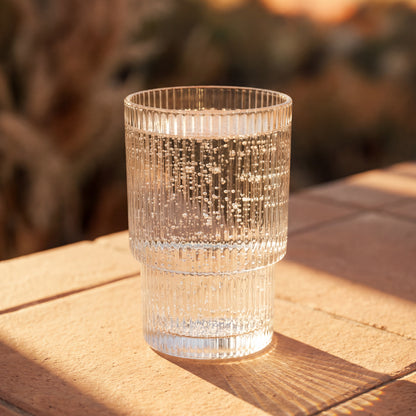 Clear textured glass on a wooden surface with a blurred natural background