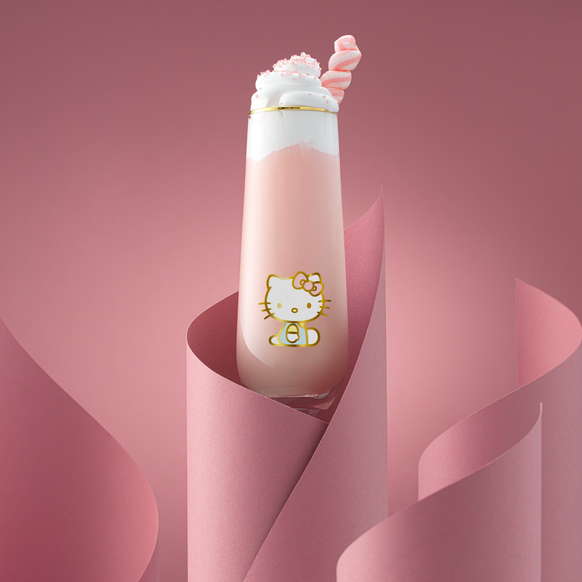 A Hello Kitty themed stemless flute filled with a pink beverage, presented against a pink backdrop.