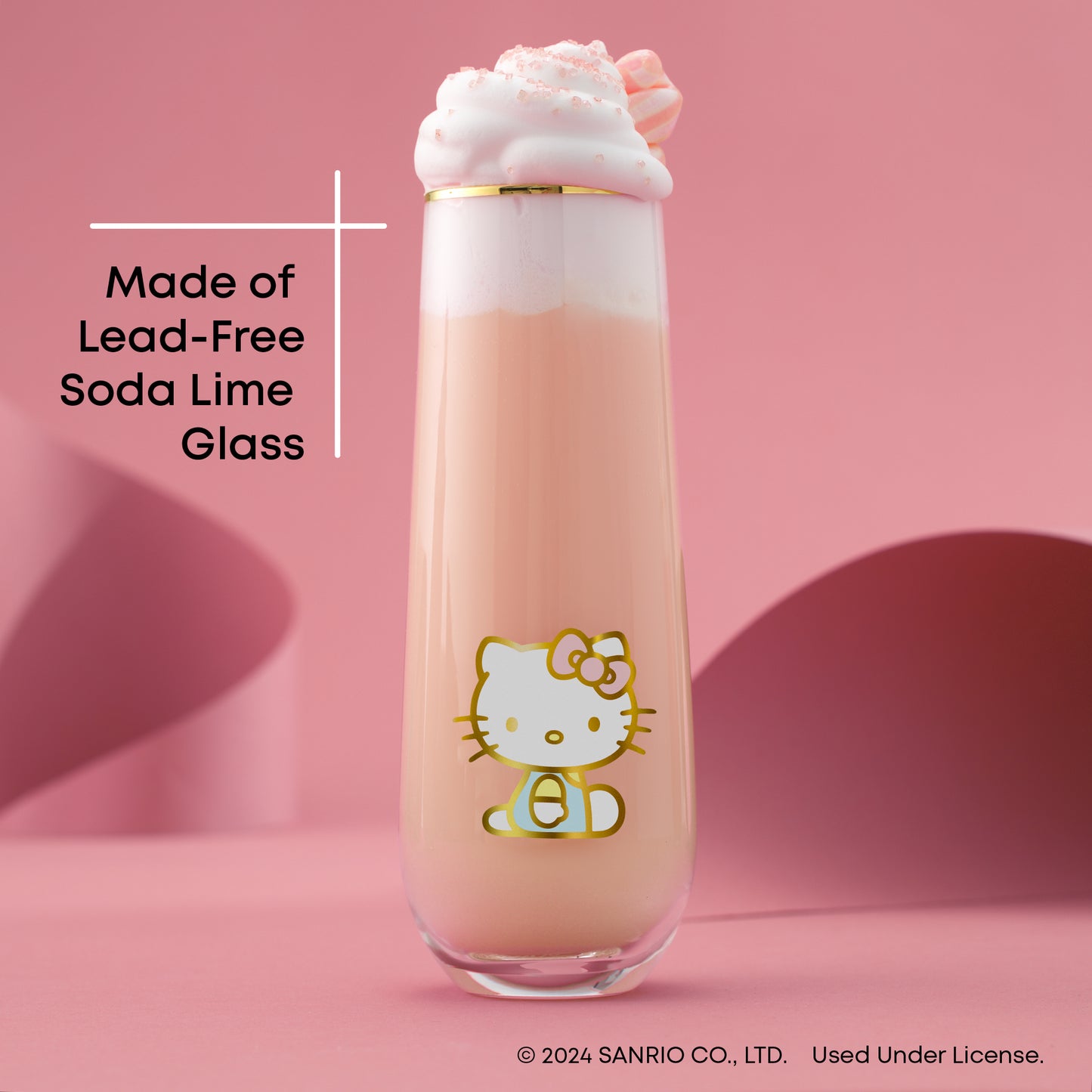 A Hello Kitty themed stemless flute filled with a pink beverage, presented against a pink backdrop, with text "made of lead free soda lime glass"