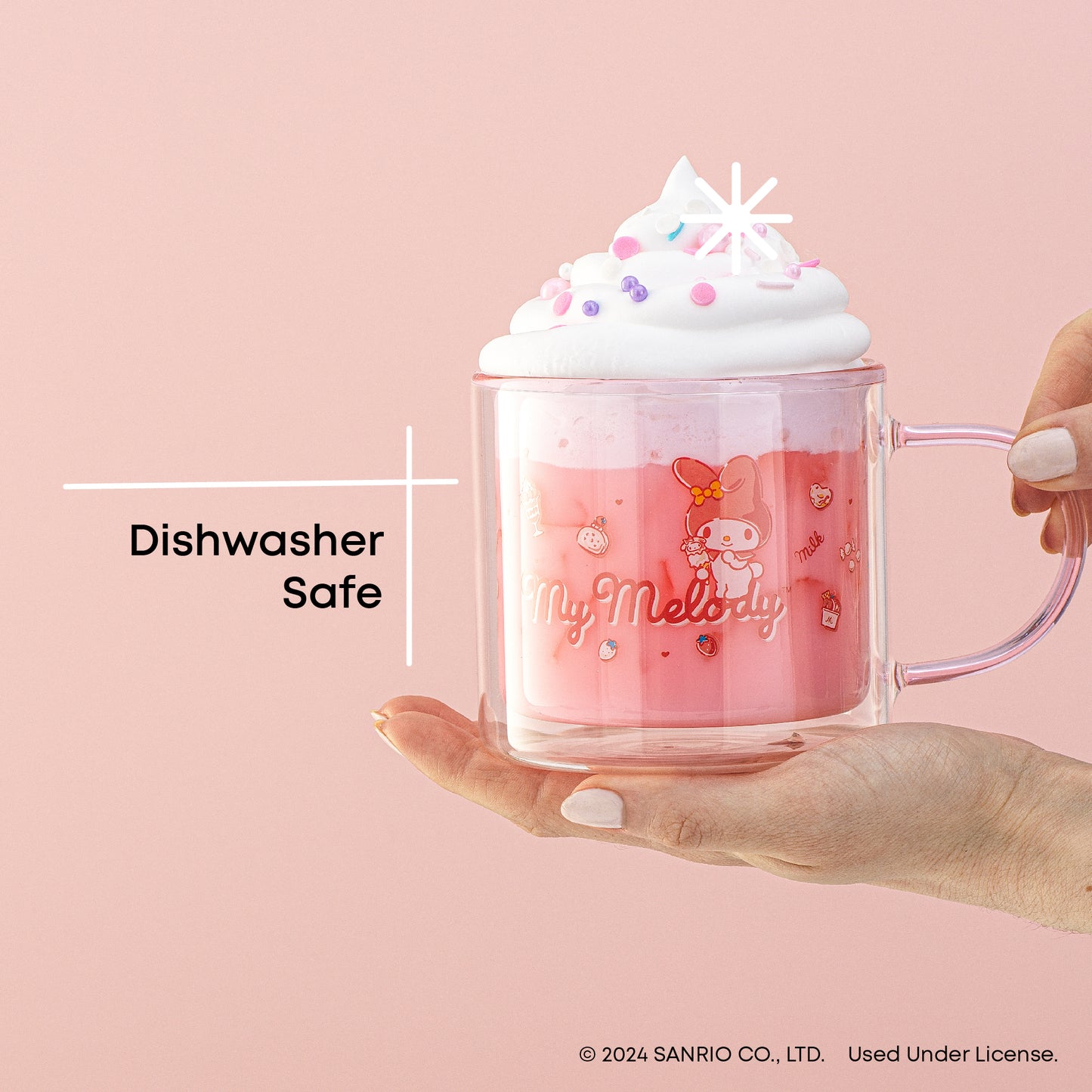 A person holding a pink My Melody mug with whipped cream on top. The mug has a white image of My Melody. Text on the image reads "Dishwasher Safe".