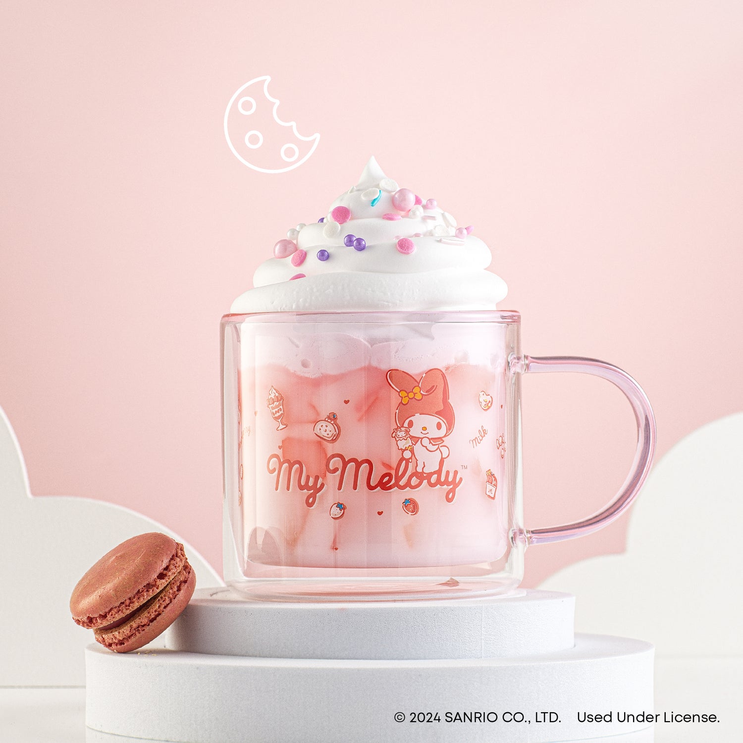 A pink JoyJolt My Melody mug filled with a creamy beverage. Next to the mug is a chocolate macaron. The mug has an image of My Melody by Sanrio.  -dt-pdp-wrappedimg