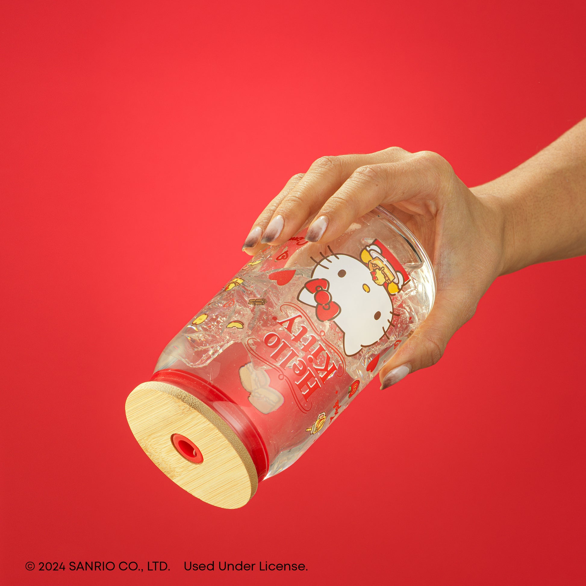 A hand holding the Hello Kitty tumbler, full of a liquid, upside down without a straw inserted to demonstrate its leakproof.