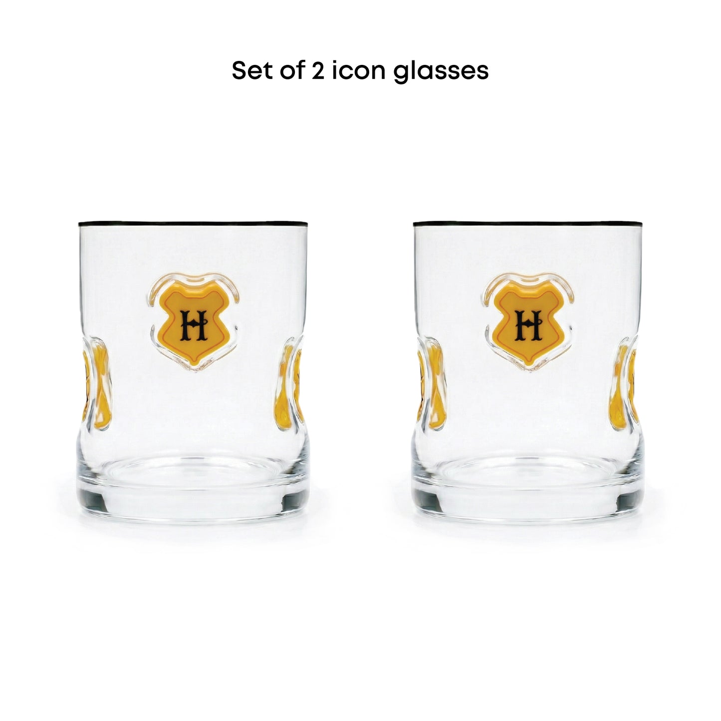Set of 2 clear glass icon tumblers with a gold crest design featuring a black letter 'H' on a white background, with black text above reading 'Set of 2 icon glasses'.