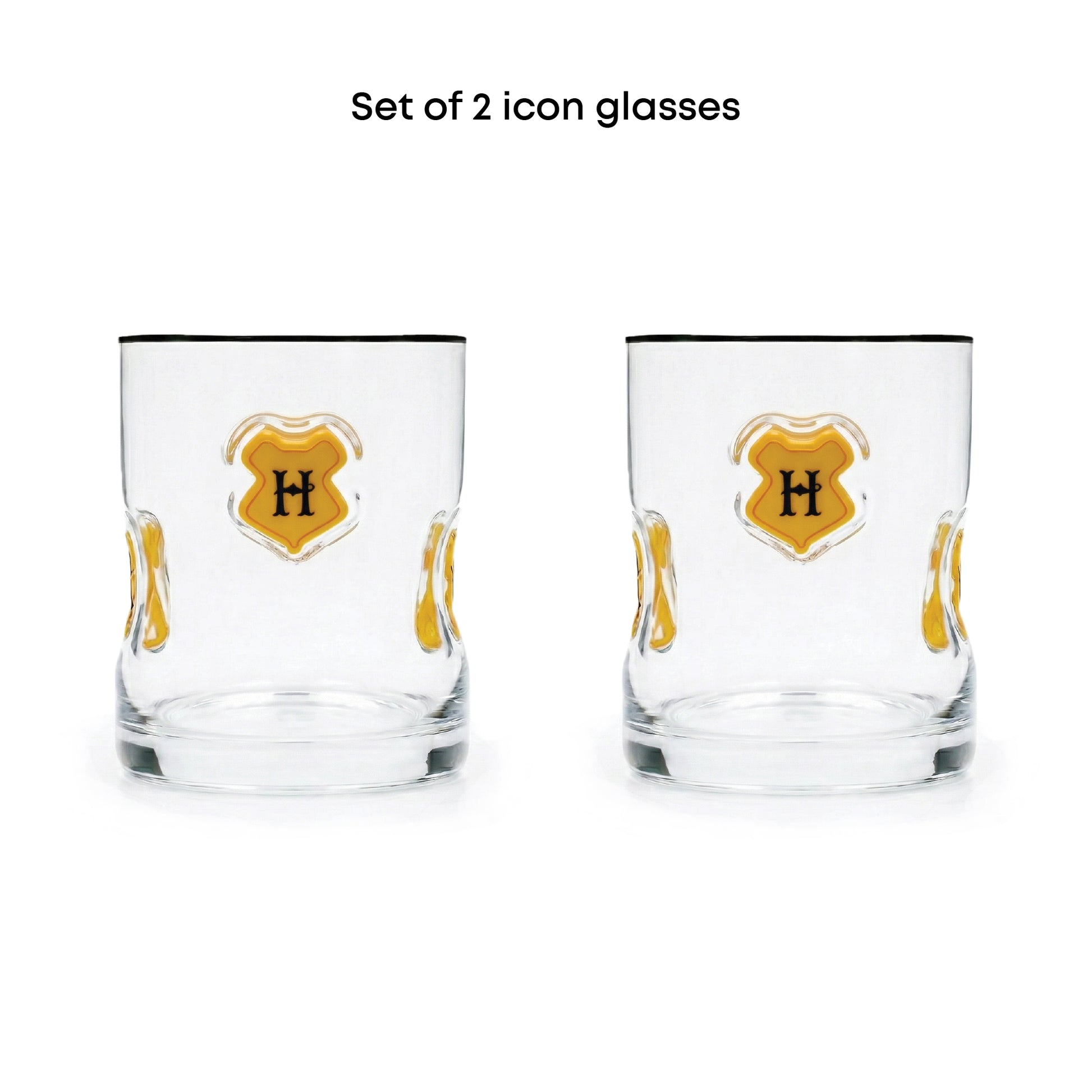 Set of 2 clear glass icon tumblers with a gold crest design featuring a black letter 'H' on a white background, with black text above reading 'Set of 2 icon glasses'.