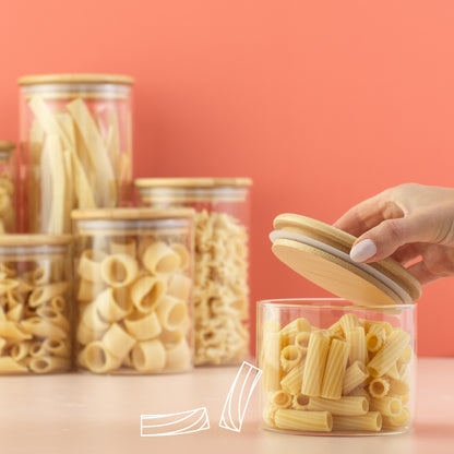 Hand opening the lid of the smallest jar filled with pasta.